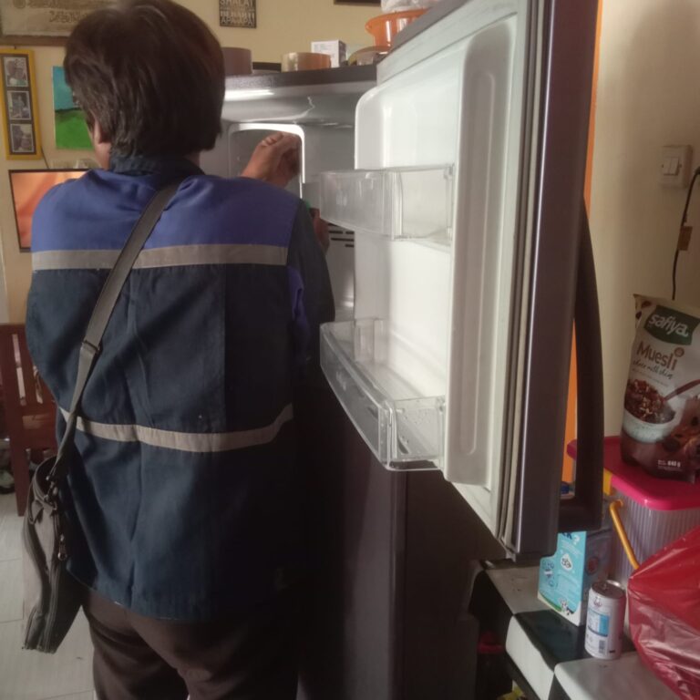 Teknisi melakukan perbaikan kulkas dua pintu pada bagian freezer
